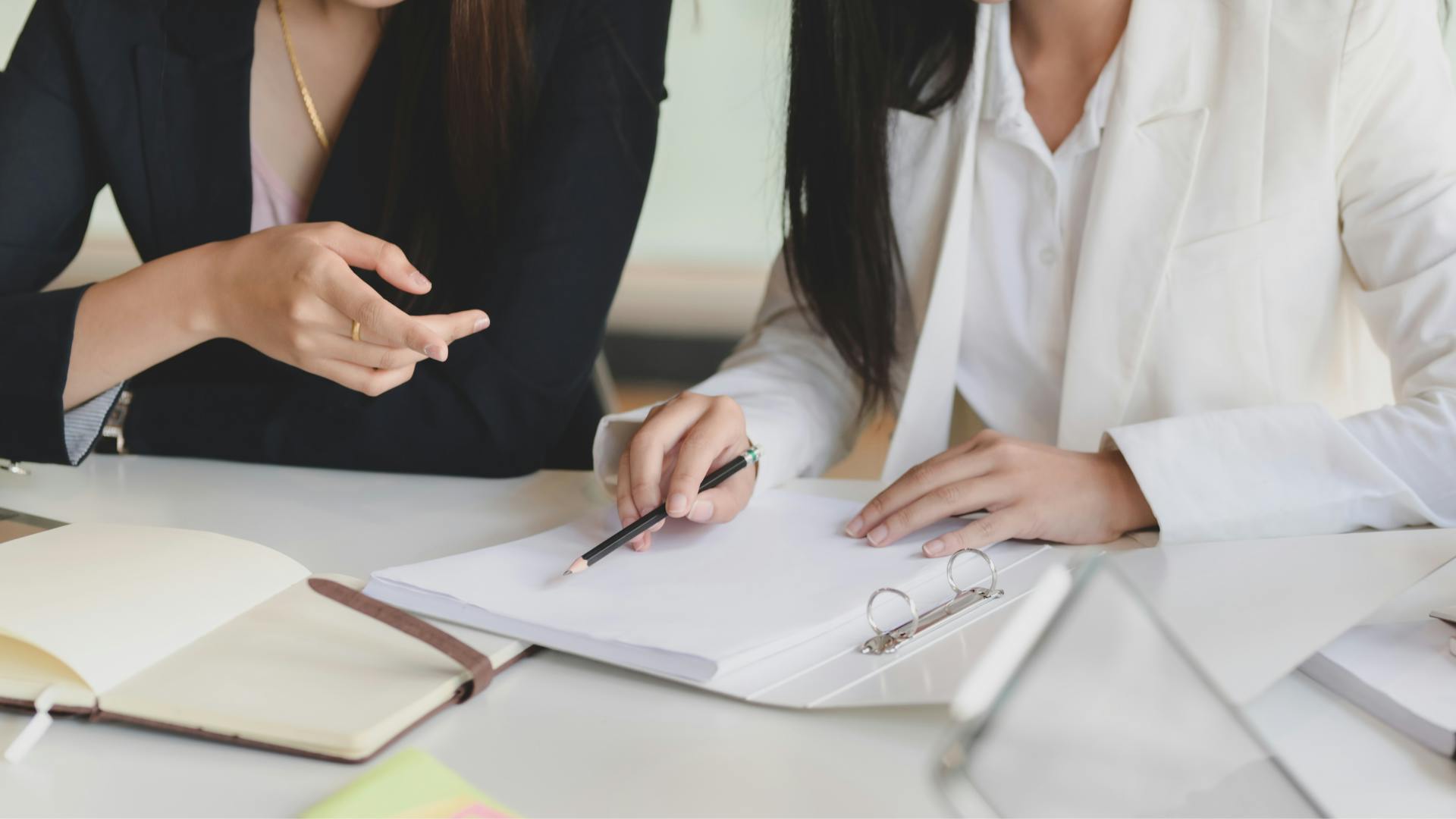 Close up of two women looking at paperwork in desk