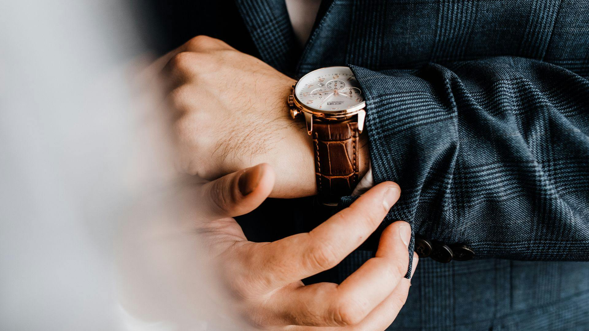 Man looking at watch, wearing a suit jacket