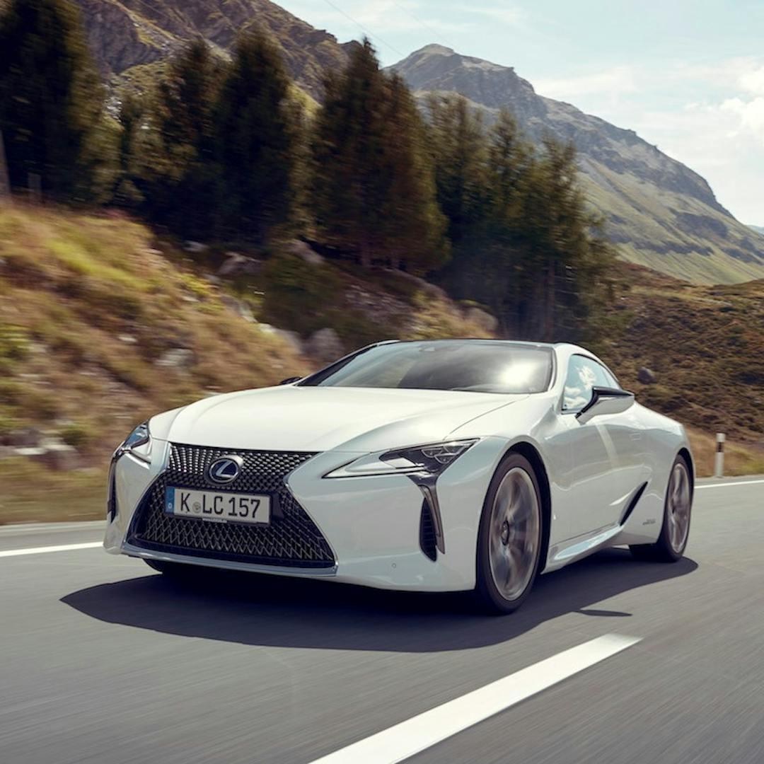 White Lexus LF-A sports car driving through scenic landscape